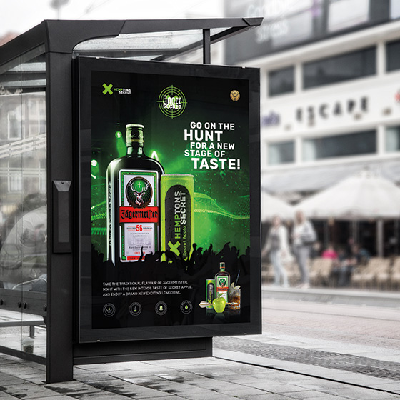 Bushaltestelle mit integrierter Plakatwand (city light), darin ein schwarze Plakat der Marke Jägersecret, mit grünen Elementen und Bildern. entworfen von Adprico, gedruckt von Druckraum A